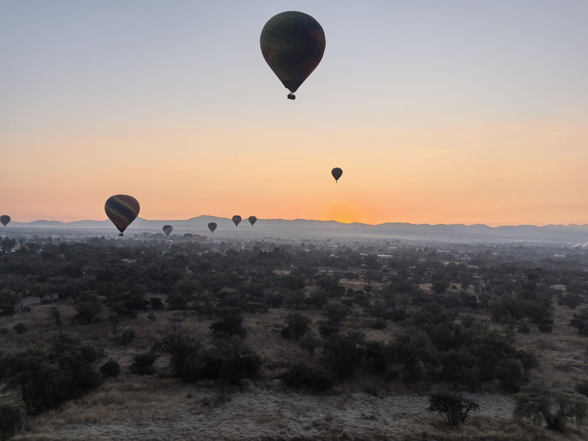 Hot air balloons floating over Teotihuacan before sunrise